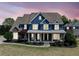 Charming two-story home with a covered front porch, manicured lawn and beautiful front yard landscaping at twilight at 302 Meadow Lark Xing, Canton, GA 30114