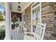 Relaxing front porch with stone facade, rocking chairs and side table create a cozy outdoor retreat at 302 Meadow Lark Xing, Canton, GA 30114