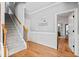 Hallway with wainscoting, wood floors, coat rack, staircase, and open doorway to bathroom at 302 Meadow Lark Xing, Canton, GA 30114