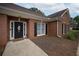 Close-up view of a red brick home featuring the front door with sidelights and black shutters at 3020 Templeton Ln, Loganville, GA 30052