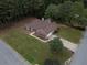 Aerial view of a red brick home with an attached garage, a large yard, and mature trees at 3020 Templeton Ln, Loganville, GA 30052