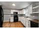 Kitchen featuring white cabinets, black appliances, wood-look floors and granite countertops at 1090 Harwell Nw St, Atlanta, GA 30314