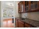 Wet bar featuring dark wood cabinets, granite countertops, and stainless steel sink at 1917 Baxley Pine Trce, Suwanee, GA 30024