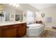 A luxurious bathroom featuring a large soaking tub, double vanity, and natural light from the window at 1917 Baxley Pine Trce, Suwanee, GA 30024