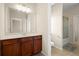 Neutral bathroom with wood cabinets, large mirror, good light, and tiled floors and walls at 1917 Baxley Pine Trce, Suwanee, GA 30024