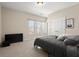 Carpeted bedroom with gray comforter, large window with blinds, and off-white colored walls at 1917 Baxley Pine Trce, Suwanee, GA 30024