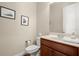 Clean powder room with a cherry vanity, white fixtures, and framed artwork at 1917 Baxley Pine Trce, Suwanee, GA 30024