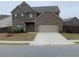 Two-story brick home with a two-car garage and well-manicured front yard on a sunny day at 212 Eleanora Way, Loganville, GA 30052