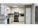 Galley kitchen featuring white cabinets, granite countertops, and stainless steel appliances at 1655 Cherry Hill Sw Rd, Conyers, GA 30094