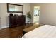 Primary bedroom with dark wooden floors, large dresser and view into the bathroom at 410 Spring Lake Hls, Canton, GA 30114