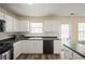 Bright eat-in kitchen with white cabinets, black appliances and countertops, with wood flooring at 63 Shadowhill Ct, Loganville, GA 30052