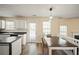 Eat-in kitchen with white cabinets, black countertops, wood floors, and stainless steel appliances at 63 Shadowhill Ct, Loganville, GA 30052