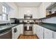 Galley kitchen with stainless steel appliances, white cabinets, dark countertops, and laminate floors at 5095 Derry Nw Rd, Acworth, GA 30101