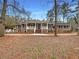 Charming brick home featuring a welcoming front porch, mature trees and landscaping at 121 Northwoods Rd, Sharpsburg, GA 30277