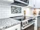 Close-up of a kitchen featuring granite countertops, stainless steel stove, and modern backsplash at 1238 Westboro Sw Dr, Atlanta, GA 30310