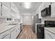 Well-lit kitchen with white cabinets, wood-look vinyl floors, and stainless steel appliances at 3645 Fay Dr, Rex, GA 30273