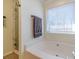 Bathroom showcasing a jetted soaking tub and marble-tiled shower, complemented by a bright window at 45 Somerset Ct, Covington, GA 30016