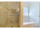 Relaxing bathroom showcasing a marble-tiled shower and a separate soaking tub by a bright window at 45 Somerset Ct, Covington, GA 30016