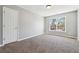 A carpeted bedroom with a double door closet and a window with view of the neighboring house at 4271 Weston Sw Dr, Lilburn, GA 30047