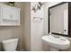 Well-lit half bathroom with pedestal sink, decorative mirror, and a nearby toilet at 844 Pool Rd, Hiram, GA 30141