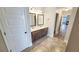 Well-lit bathroom with double sinks, brown cabinets, and tile floors, exuding style at 2897 Austin Common Dr, Dacula, GA 30019