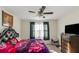 Bedroom with ceiling fan, window with curtains, dresser, and a large leather bed with colorful floral blanket at 294 Broder Farms Dr, Stockbridge, GA 30281