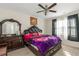 Bedroom with ceiling fan, window with curtains, dresser, and a large leather bed with colorful floral blanket at 294 Broder Farms Dr, Stockbridge, GA 30281