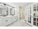 Bright bathroom features dual sinks, white cabinets, tiled floors, and glass french doors at 1056 Shady Valley Ne Pl, Brookhaven, GA 30324