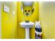 Bright half bathroom featuring yellow walls, a pedestal sink, and a round mirror at 1709 Creel Ln, Atlanta, GA 30349