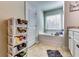 Bright bathroom featuring a tub, tiled floor, and storage shelves next to a white door at 1709 Creel Ln, Atlanta, GA 30349