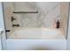 Modern bathroom with white tub, gray marble tile surround, and stylish black hardware at 3445 Stratford Ne Rd # 2504, Atlanta, GA 30326
