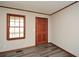 Neutral room showcasing gray wood-look floors, a window, and a wood door with brass hardware at 4800 Timber Ridge Dr, Douglasville, GA 30135