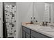 Bathroom featuring double sinks, gray cabinets, a shower/tub combo, and a decorative shower curtain at 6028 Providence Dr, Union City, GA 30291