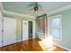Light-filled bedroom featuring green walls, hardwood floors, ceiling fan and frosted glass door closet at 1627 Walker Ave, College Park, GA 30337