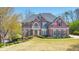 Beautiful brick home featuring a well-manicured lawn, an American flag, and mature trees at 4073 Hickory Fairway Dr, Woodstock, GA 30188