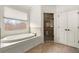 Bright bathroom boasts soaking tub with garden view, walk-in shower with glass door, and tile flooring at 13142 Overlook Pass, Roswell, GA 30075