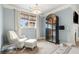 Bright bedroom features hardwood floors, natural light, lounge chair with ottoman, and stylish display cabinet at 13142 Overlook Pass, Roswell, GA 30075