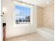 Bright bathroom featuring a large window with a city view, a soaking tub, and neutral tiling at 195 14Th Ne St # Ph 306, Atlanta, GA 30309