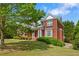 Side view of the red brick home showing landscaping, a well-manicured lawn, and a glimpse of the driveway at 711 Wilhaven Ct, Loganville, GA 30052