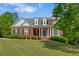 Traditional brick home featuring a welcoming front porch with white columns and a beautifully manicured lawn at 711 Wilhaven Ct, Loganville, GA 30052