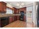 Kitchen with dark wood cabinets, dark appliances, tile backsplash, and wood floors at 711 Wilhaven Ct, Loganville, GA 30052