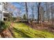 Spacious, green backyard featuring a stone retaining wall, trees, and lush greenery at 740 Frank Kirk Nw Rd, Kennesaw, GA 30152