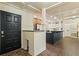 Open-concept kitchen with dark island, granite counters, stainless appliances, and a stylish black front door at 706 Barrington Hills Dr, Atlanta, GA 30350