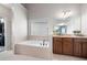 Bright bathroom featuring a large soaking tub, window, and double vanity with granite countertops at 65 Turtle Rock Cv, Acworth, GA 30101