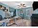 Home office featuring blue walls, hardwood floors, large windows, ceiling fan, and a work area with two monitors at 931 Cornwall Sw Ct, Marietta, GA 30064