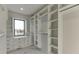 Spacious walk-in closet with custom shelving, drawers, a window for natural light, and marble floors at 2329 Walker Dr, Lawrenceville, GA 30043