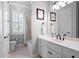 Bright bathroom with white cabinets, dual mirrors, tiled shower/tub and a large window with plantation shutters at 948 Saint Lyonn Cts, Marietta, GA 30068