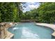 Beautiful outdoor pool area with stone waterfall feature surrounded by lush greenery and landscaping at 948 Saint Lyonn Cts, Marietta, GA 30068