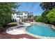 Back of home with a large in-ground pool surrounded by landscaped yard, lounge chairs, and a stone patio at 948 Saint Lyonn Cts, Marietta, GA 30068