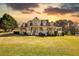 Charming two-story home with a spacious porch and well-manicured lawn with the sun setting at 2002 Orchard Terrace, Loganville, GA 30052